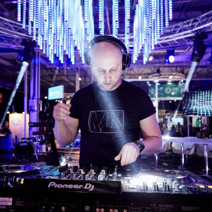 DJ arbetar vid mixer och spelare under blå och lila eventbelysning